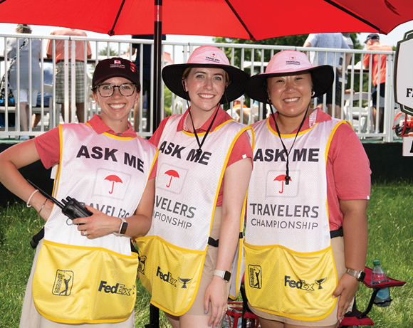 three women in volunteer aprons on a golf course